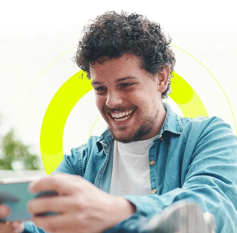 Young man with a beard smiles while looking at his phone outside, happy about job roles on TalentNext.