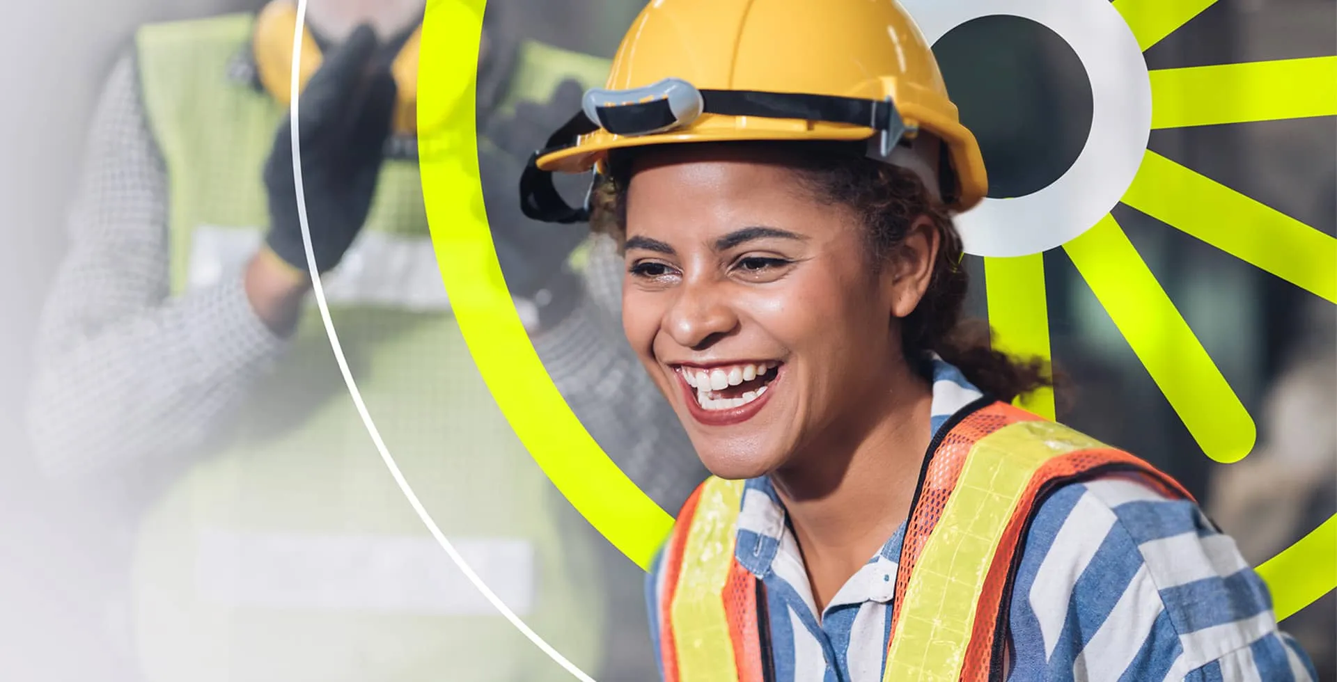 A happy young manufacturing worker in a hard hat and high-vis vest.