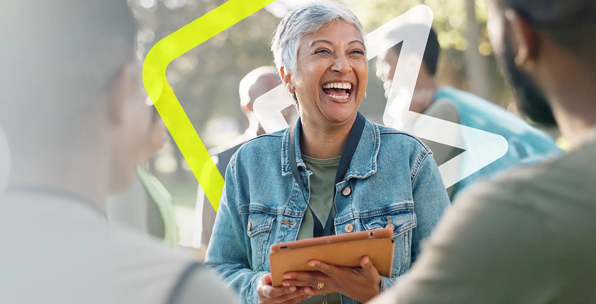 woman stood outside holding a tablet and laughing as she interacts with people around her, content with finding her next role on the TalentNext platform.