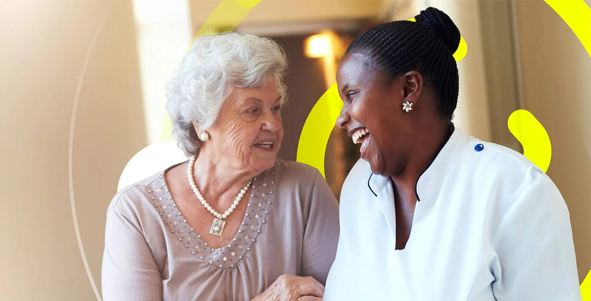 A healthcare professional warmly conversing and sharing a smile with an elderly woman.